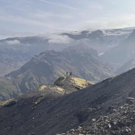 Hikers on a mountain ridge in Iceland with scenic mountain views.