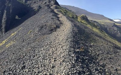 Rugged mountain trail in Iceland with rocky terrain and clear blue sky.