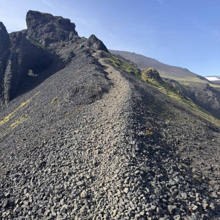 Rugged mountain trail in Iceland with rocky terrain and clear blue sky.