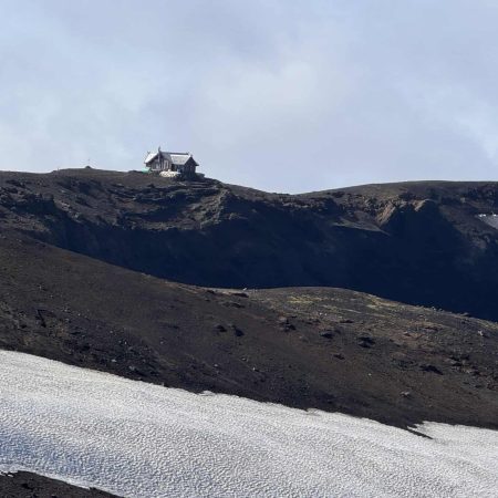 Remote mountain cabin on a snowy and rocky landscape in Iceland.