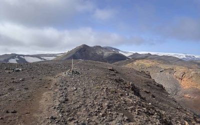 Rugged volcanic terrain in Iceland with snow-capped peaks in the background.
