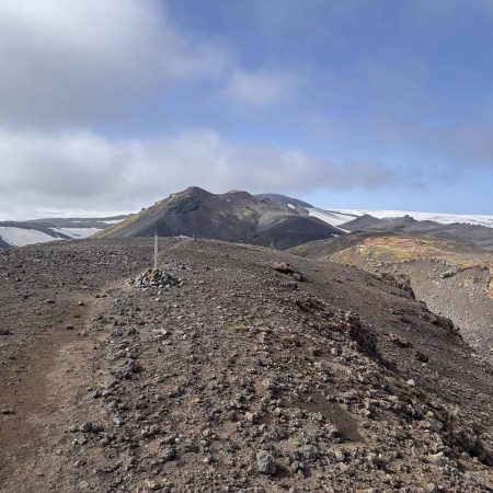 Rugged volcanic terrain in Iceland with snow-capped peaks in the background.