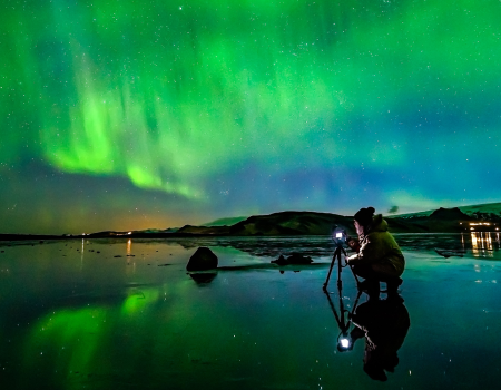 Northern-Lights_Woman-taking-photo-at-Dyrholaey-sea-cliffs_Photographer-Snorri-Thor-Tryggvason_x-large-1680x840-1