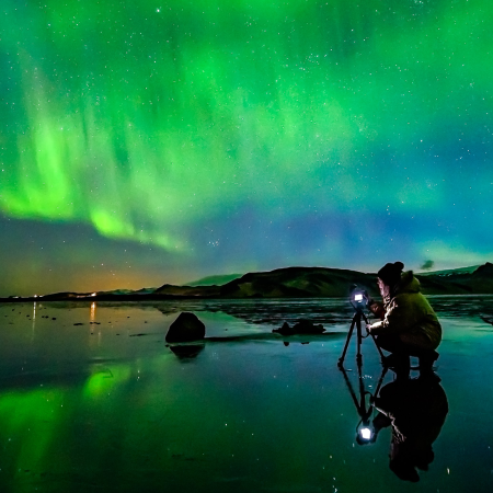 Northern-Lights_Woman-taking-photo-at-Dyrholaey-sea-cliffs_Photographer-Snorri-Thor-Tryggvason_x-large-1680x840-1