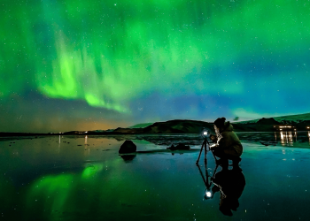 Northern-Lights_Woman-taking-photo-at-Dyrholaey-sea-cliffs_Photographer-Snorri-Thor-Tryggvason_x-large-1680x840-1