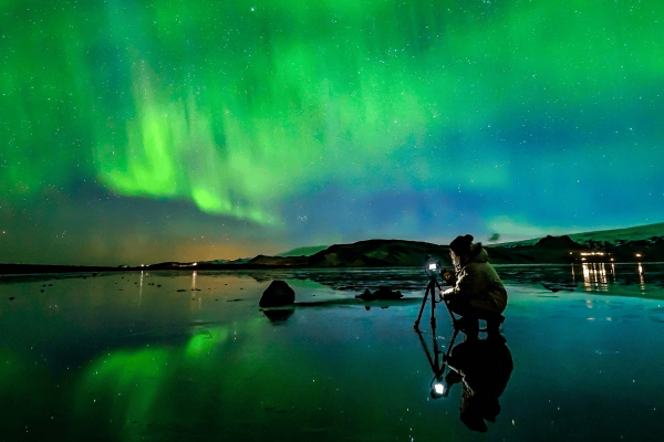 Northern-Lights_Woman-taking-photo-at-Dyrholaey-sea-cliffs_Photographer-Snorri-Thor-Tryggvason_x-large-1680x840-1
