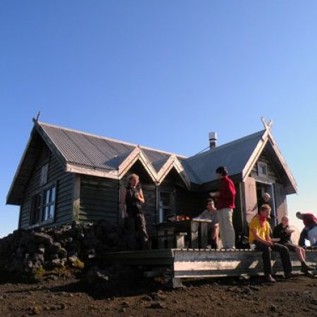 Group of hikers relaxing outside a mountain cabin during Icetrek expedition.